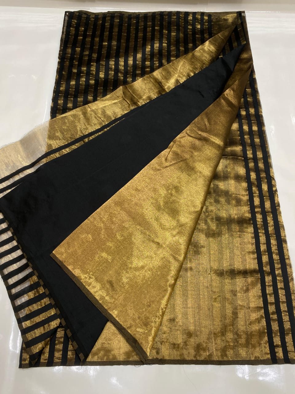 Golden Chanderi Handloom Pattu Tissue Silk Saree With Elegant Black Striped Weaving, Rich Tissue Finish, Stylish Woven Border And Matching Blouse Piece.