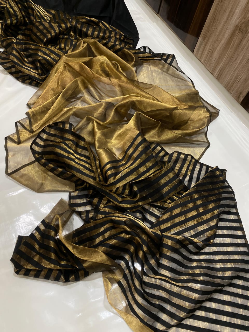 Golden Chanderi Handloom Pattu Tissue Silk Saree With Elegant Black Striped Weaving, Rich Tissue Finish, Stylish Woven Border And Matching Blouse Piece.