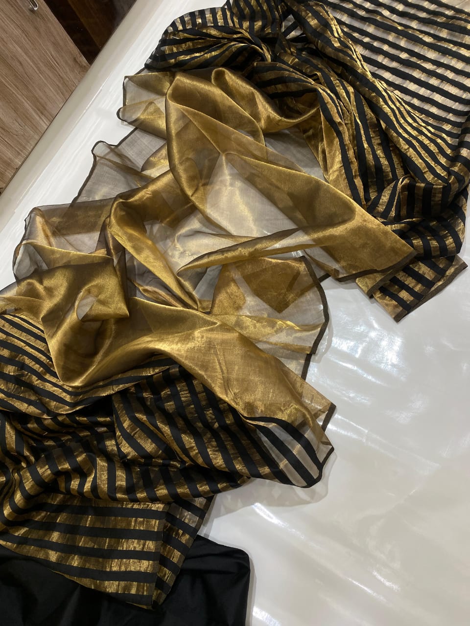 Golden Chanderi Handloom Pattu Tissue Silk Saree With Elegant Black Striped Weaving, Rich Tissue Finish, Stylish Woven Border And Matching Blouse Piece.