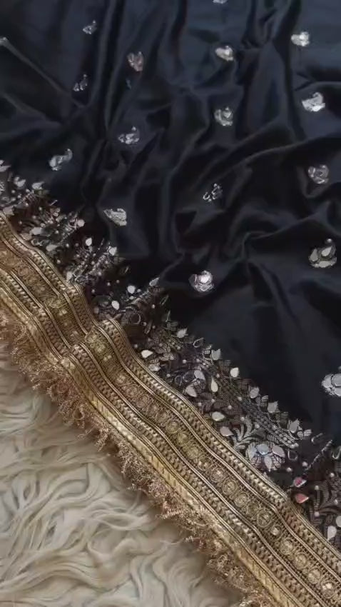 Black Banarasi Soft Silk Woven Saree featuring intricate mirror handwork, elegant Rajkumari lace border, woven paisley motifs, richly embellished pallu, and matching blouse piece, perfect for weddings, festive occasions, receptions, and party wear.